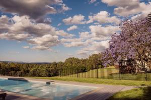a house with a swimming pool and a tree at Wine Country Villas in Pokolbin
