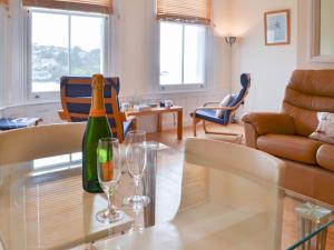 a wine bottle and two glasses on a glass table in a living room at Tides Reach in Fowey