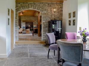 a dining room with a table and chairs and a stone wall at The Old Cider Mill in Llanstephan