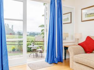a living room with blue curtains in front of a sliding glass door at The Bothy in Mathon