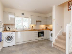 a white kitchen with a sink and a dishwasher at The Bothy in Mathon +20 photos