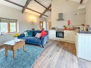 a living room with a blue couch and a kitchen at Nuthatch Barn in Pancrasweek