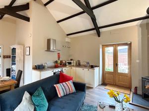 a living room with a blue couch and a kitchen at Nuthatch Barn in Pancrasweek