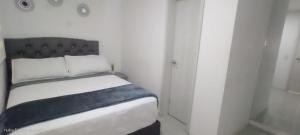 a white bedroom with a bed with a black headboard at Room cerca al aeropuerto #5 in Bogotá +10 photos