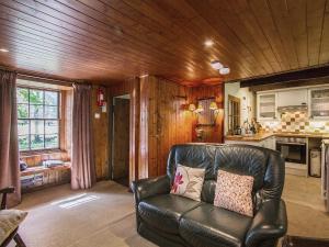 a leather couch in a living room with a kitchen at Gardener's Bothy in Balnaboth