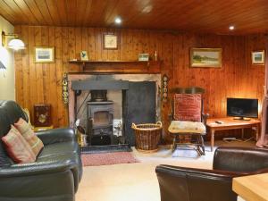 a living room with a fireplace and a couch at Gardener's Bothy in Balnaboth