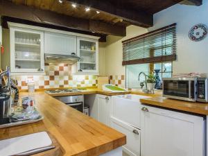 a kitchen with white cabinets and a wooden counter top at Gardener's Bothy in Balnaboth +4 photos
