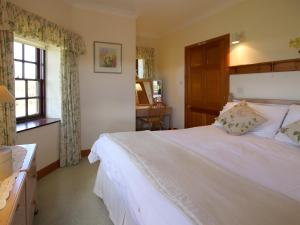 a bedroom with a white bed and a window at Conheath Gatelodge Cottage in Kingholm Quay