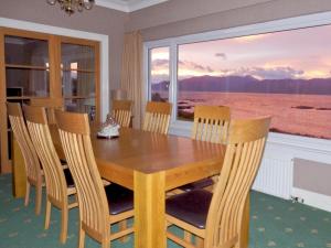 a dining room table and chairs with a view of the ocean at Macinnisfree Cottage in Saasaig