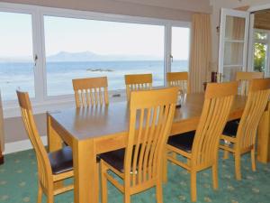 a dining room table and chairs with a view of the ocean at Macinnisfree Cottage in Saasaig +8 photos