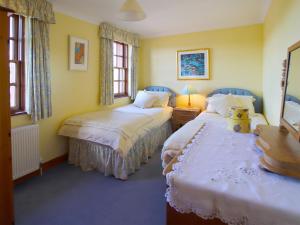 two beds in a room with yellow walls and windows at Conheath Gatelodge Cottage in Kingholm Quay