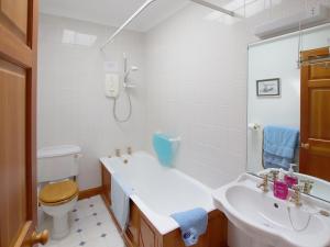 a white bathroom with a sink and a toilet at Conheath Gatelodge Cottage in Kingholm Quay +2 photos