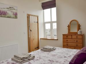 a bedroom with a bed and a mirror and a dresser at Bess's Cottage in Middlewich