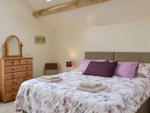 a bedroom with a bed with purple and purple pillows at Bess's Cottage in Middlewich