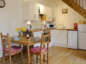 a kitchen with white cabinets and a wooden table with chairs at Bess's Cottage in Middlewich
