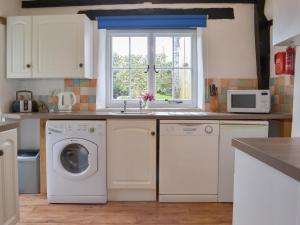 a kitchen with a washing machine and a window at Meadwell in Treknow