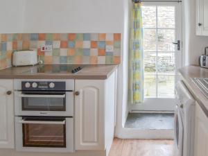 a kitchen with a stove and a sink and a window at Meadwell in Treknow