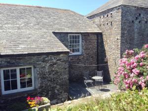 a stone house with two chairs and a window at Meadwell in Treknow +2 photos