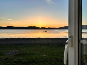 a view from a window of a sunset over the water at Point Park in Taynuilt
