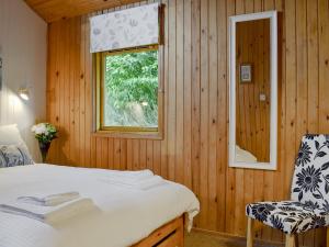 a bedroom with a bed and a window and a chair at Loch Earn View Lodge in Lochearnhead