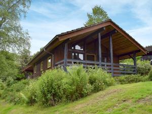 a large wooden house on a hill with grass at Loch Earn View Lodge in Lochearnhead +7 photos