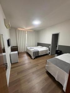 a hotel room with two beds and a television at Parada Guanabara in Belo Oriente