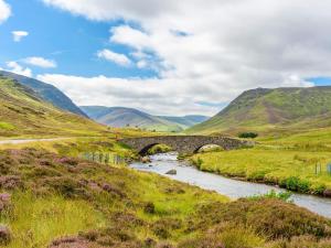 a stone bridge over a river in the hills at Glentairre Cottage - Swww in Balnaboth