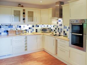 a kitchen with white cabinets and blue tiles on the wall at Achabeg - S4597 in Taynish +10 photos