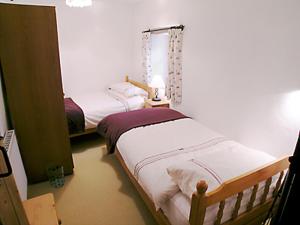 a bedroom with two beds and a lamp in it at Purlinney in Treknow +3 photos