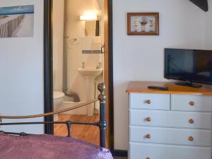 a bedroom with a dresser with a television and a bathroom at Purlinney in Treknow