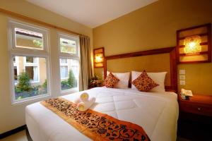 a bedroom with a large white bed with two windows at Sari Villa Ubud in Ubud +60 photos