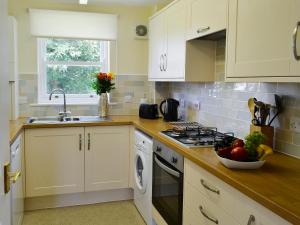 a kitchen with white cabinets and a bowl of fruit on the counter at Flat 2 Lonsdale House in Keswick