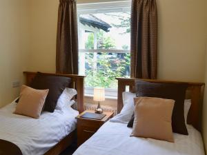 two beds in a room with a window at Flat 2 Lonsdale House in Keswick