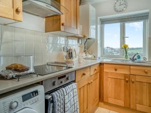 a kitchen with a stove top oven next to a window at Granary Cottage - Uk10695 in Amroth