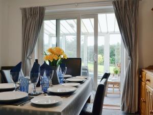 a table with chairs and a table with plates and glasses at Hillside Cottage in Keswick