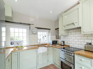 a kitchen with white cabinets and white appliances at Pinfold Cottage in Richmond