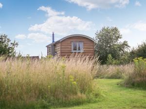 a small wooden cabin in a field of tall grass at Ryeland Hut - Qu7632 in Messing