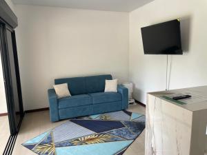 a living room with a blue couch and a flat screen tv at Tycoon Luxury, SPA Privatif, Lit XXL, Cinema in Matoury