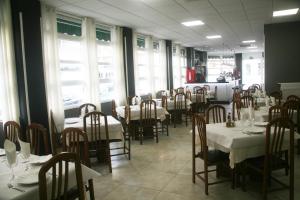 a dining room with tables and chairs and windows at Hostal El Altet in El Alted