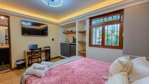 a bedroom with a bed and a desk and a kitchen at Primavera Lofts in Medellín