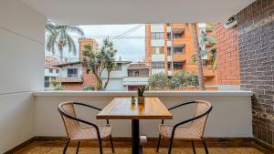 a table and chairs on a balcony with a window at Primavera Lofts in Medellín
