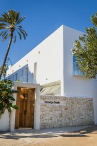 a white building with a palm tree in front of it at Vacança beach in Denia