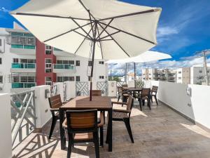 a table and chairs with an umbrella on a balcony at Colinas del Sol Res perfect in Jacagua