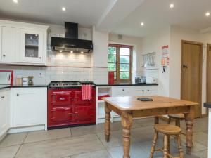 a kitchen with a red stove and a wooden table at Brook House in Mathon +22 photos