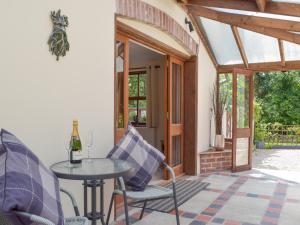 a patio with a table and chairs and a window at Woodpecker Rest in Cilgerran