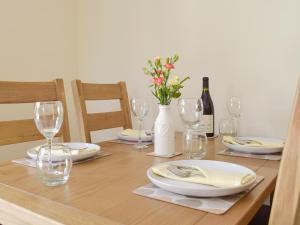 a table with plates and glasses and a bottle of wine at Woodpecker Rest in Cilgerran