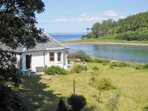 a small white house on the side of a river at Shore Cottage - S4600 in Tarbert