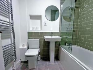 a bathroom with a toilet and a sink and a tub at 10 Elm Court in Keswick +1 photo