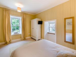 a bedroom with a white bed and two windows at The Cottage in Bankfoot