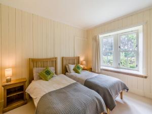 two beds in a bedroom with a window at The Cottage in Bankfoot